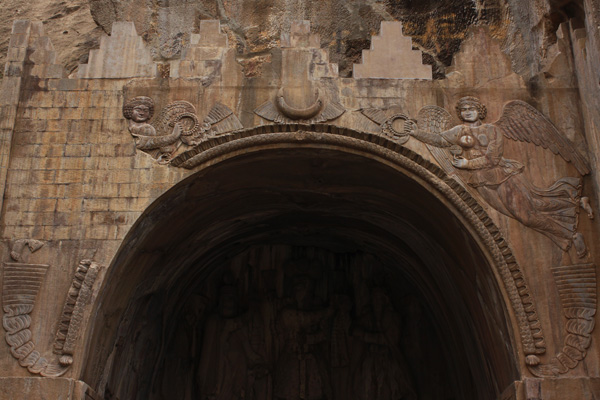 بر فراز تاق دو فرشته که نماد پیروزی هستند دیده می‌شوند و در بین آن‌ها نقش هلال ماه به چشم می‌خورد. این هلال از رازهای تاق بستان است و چیستی آن در ابهام قرار دارد.
